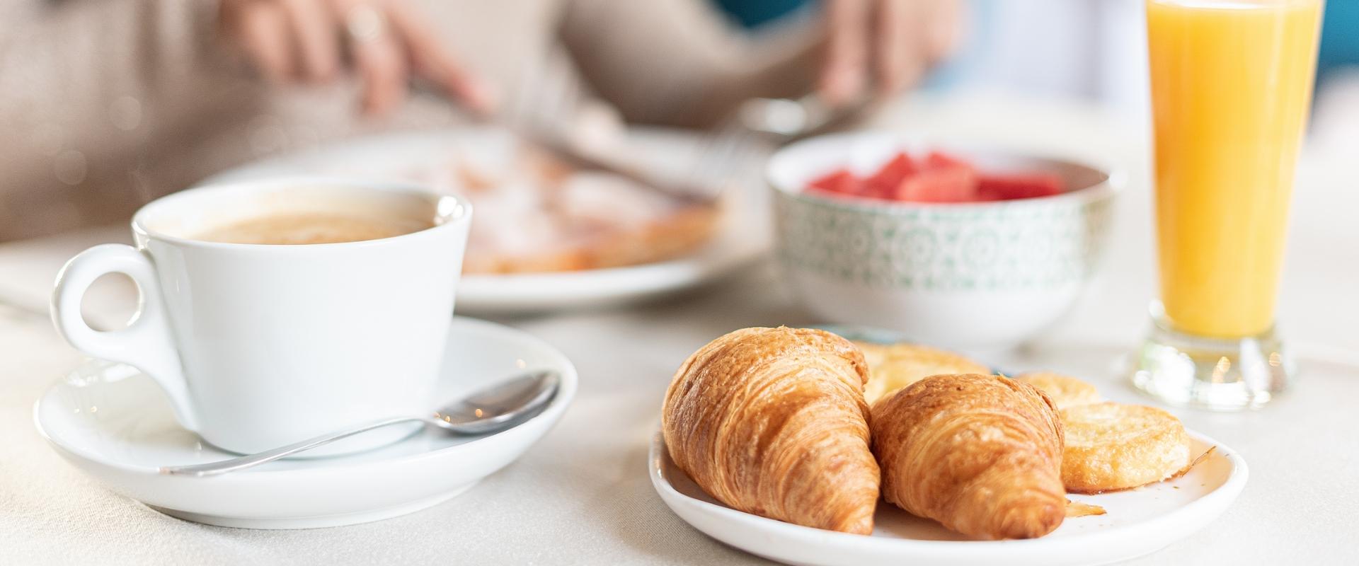 Tazza di caffè espresso e croissant su un tavolo di legno.